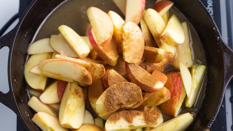 apples, cinnamon, and apple juice in cast-iron pan