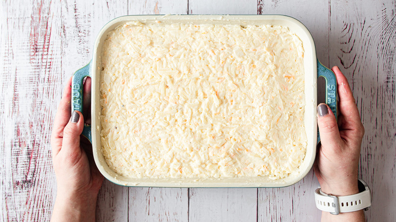 hands holding casserole dish before baking