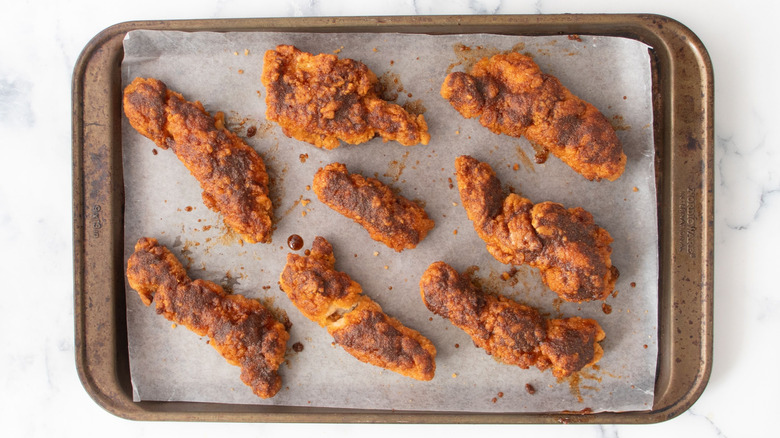 Spice coated chicken tenders on baking sheet