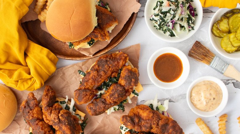 Various spicy chicken sandwiches with slaw, bowls of sauce