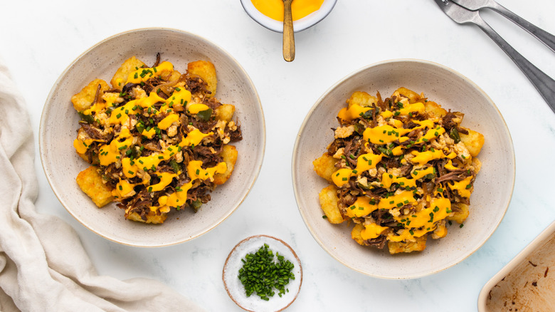 Two bowls of hash brown brisket scramble with cheese sauce