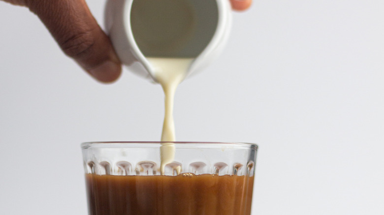 Milk being poured into glass of coffee