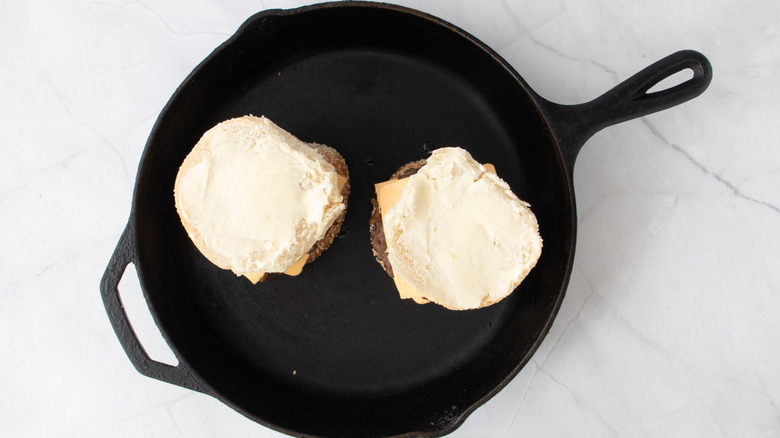 Burgers with buttered buns in skillet