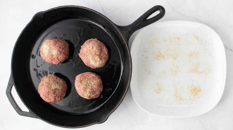 Beef balls in skillet next to white plate