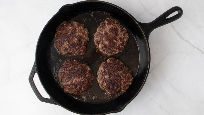 Cooked beef patties in skillet