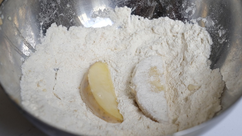 Dipping the potato wedges into the seasoned flour