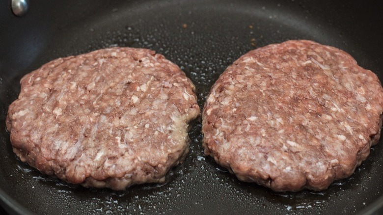 A pair of patties cooking in a pan