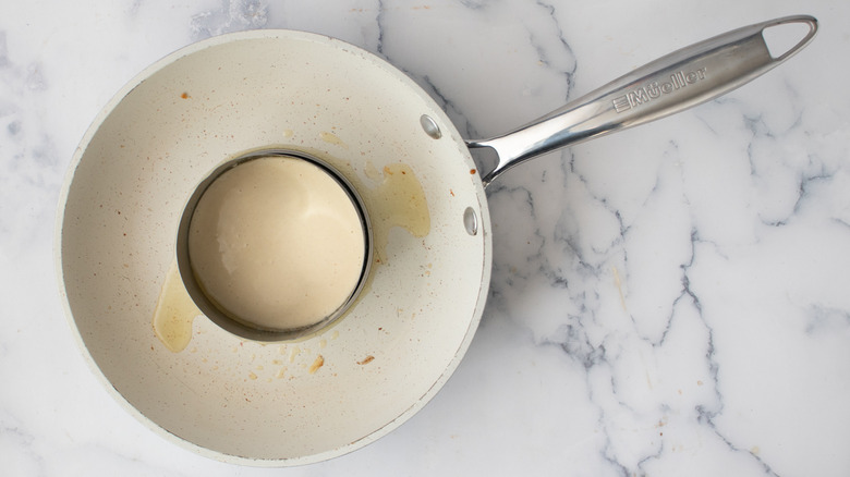 Batter inside a metal ring mold inside a white frying pan