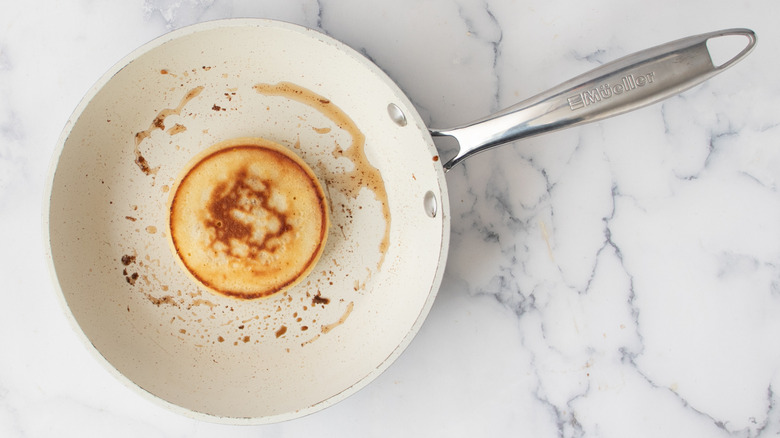 Cooked pancake inside a metal ring mold inside a white frying pan