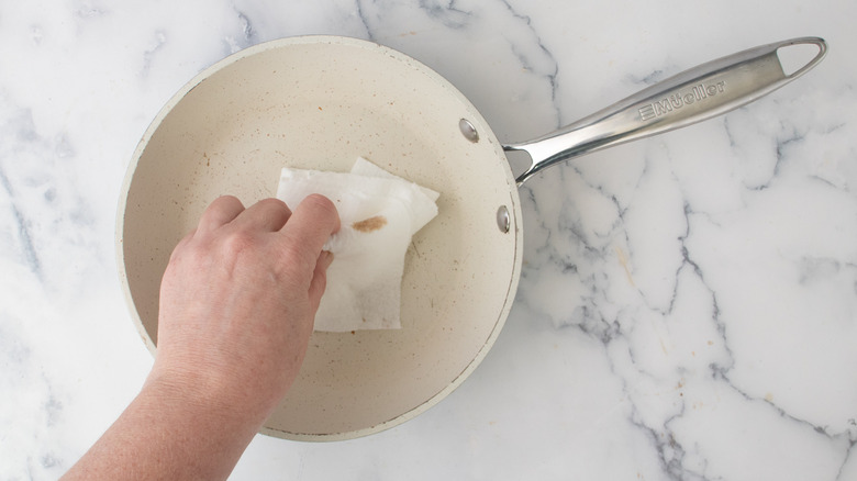 Hand wiping out frying pan