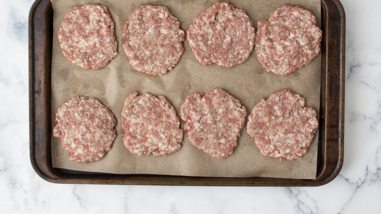 Uncooked sausage patties in a metal baking pan