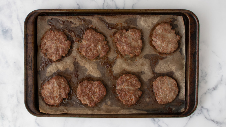 Cooked sausage patties in a metal baking pan