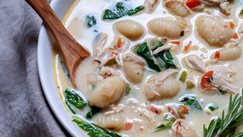 A wooden spoon sits in a bowl of soup