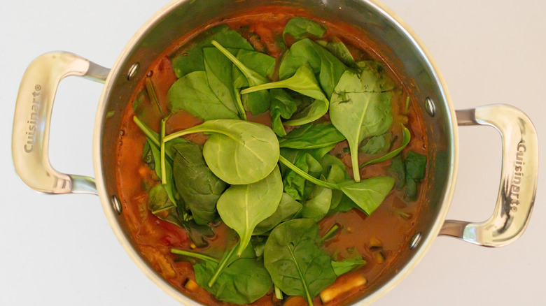 pot of soup with spinach on top melting into it