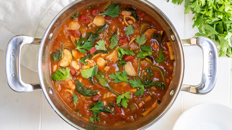 minestrone soup in pot garnished with parsley