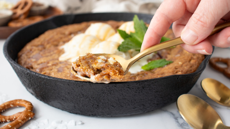 Hand spooning up skillet cookie