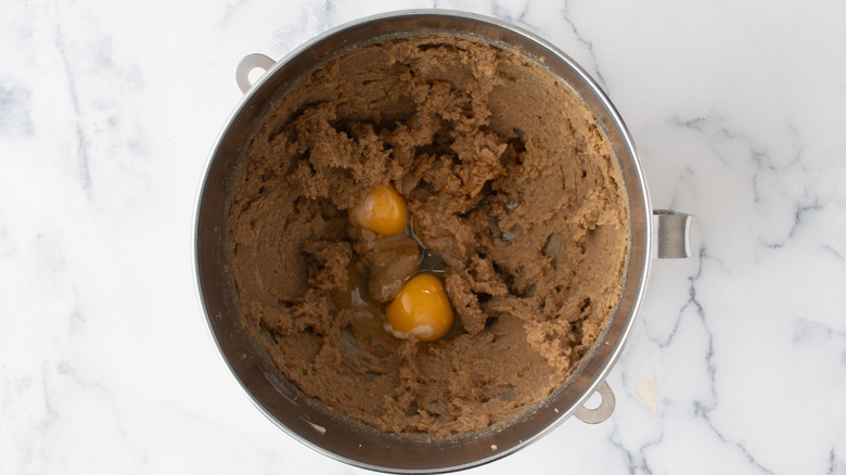 Brown sugar and butter mixture in a metal bowl with two raw eggs