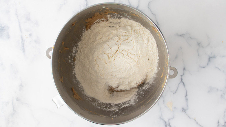 Brown sugar and butter mixture partially covered with flour in a metal bowl