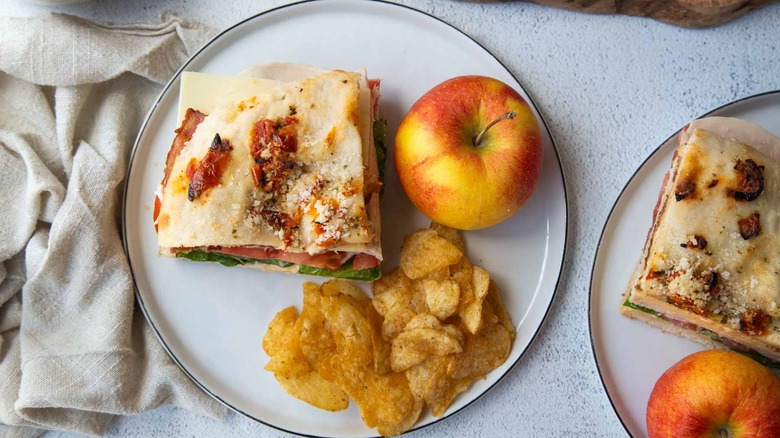 focaccia sandwich with chips and an apple