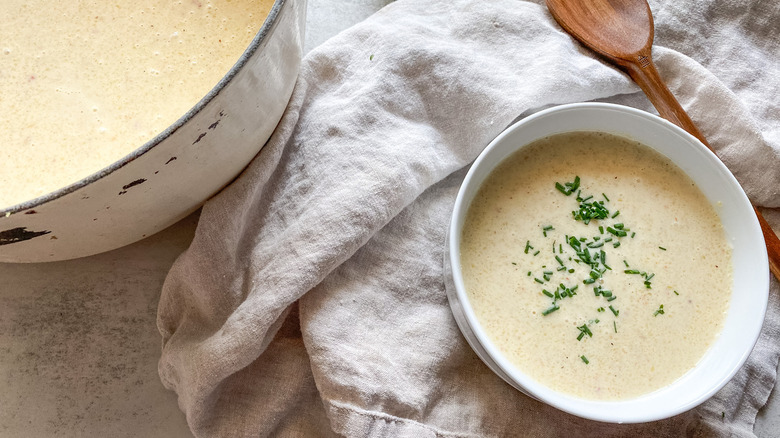 Soup topped with chives next to pot