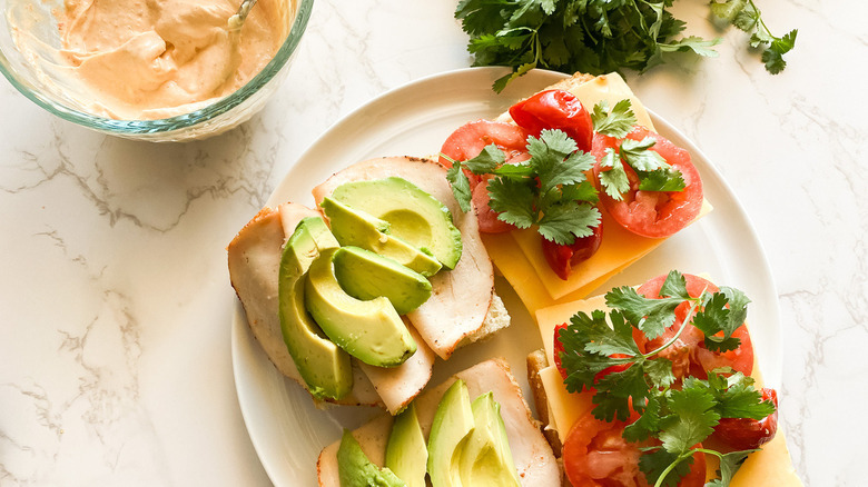 open chipolte chicken sandwich with avocado on plate