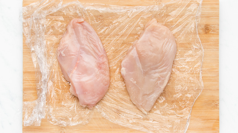 flattened chicken breasts on cutting board