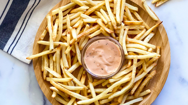 Copycat Raising Cane's sauce with fries around it on platter