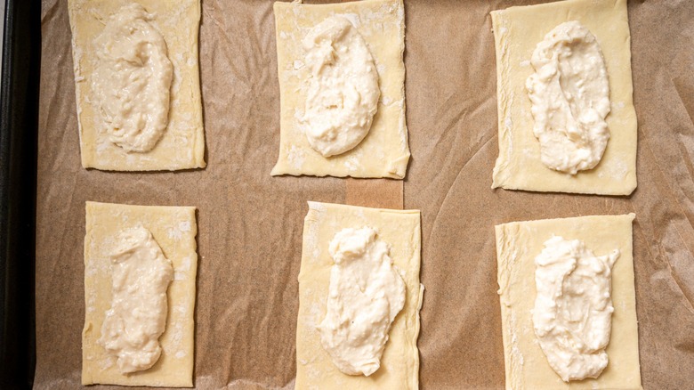 uncooked cream cheese danishes on parchment-lined tray