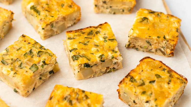 Squares of potato chive bake on parchment-lined cutting board