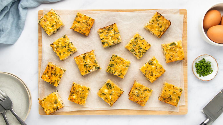 Squares of potato chive bake on parchment-lined cutting board