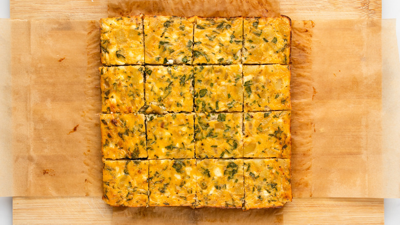 Sliced potato chive bake in wooden cutting board