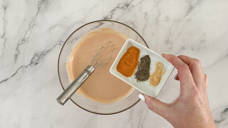 hand holding spices over bowl