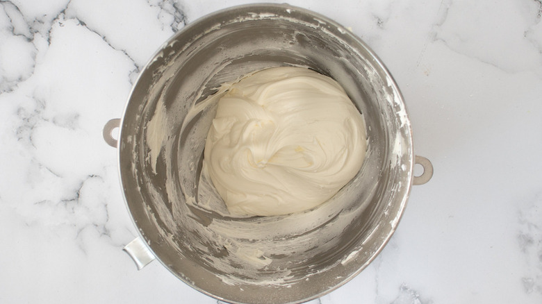 white frosting in metal bowl