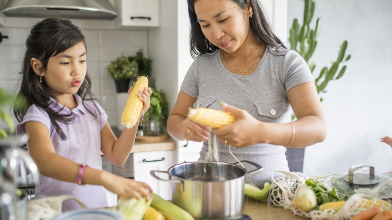 Mother and daughter preparing corn
