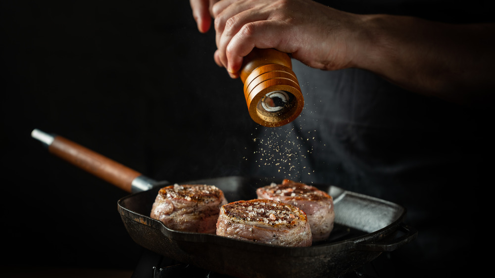 Person seasoning a steak 