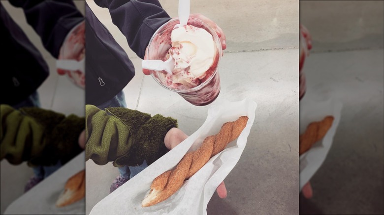 Person holding Costco churro and sundae