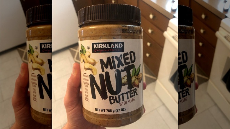 Hand holding Kirkland mixed nut butter jar