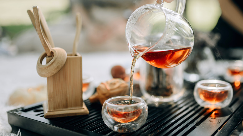 Person pouring tea into tea cups