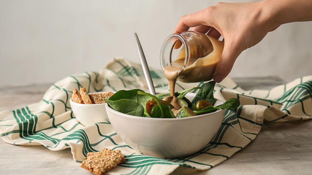 Person pouring dressing onto salad