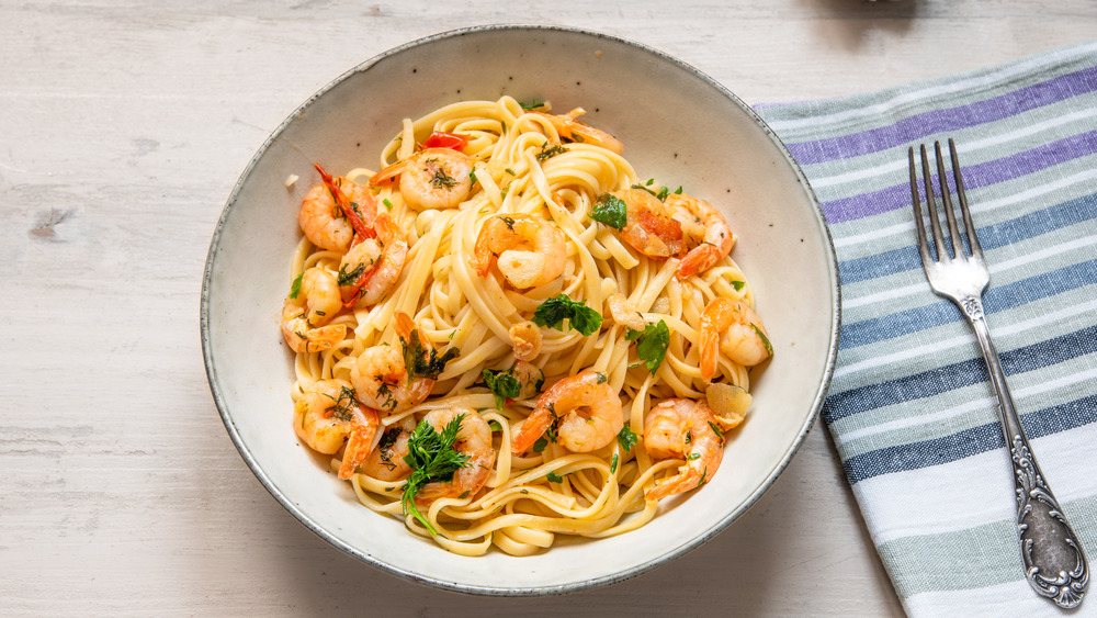 Bowl of shrimp scampi with pasta on table