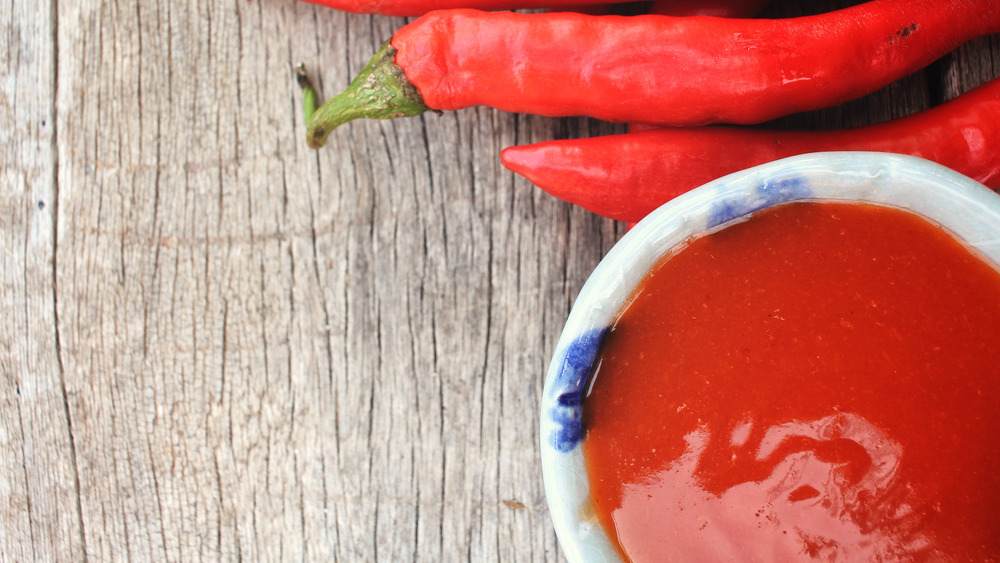 Sriracha and peppers on wood