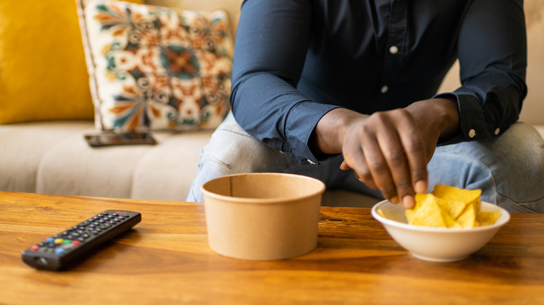 man eating chips from bowl