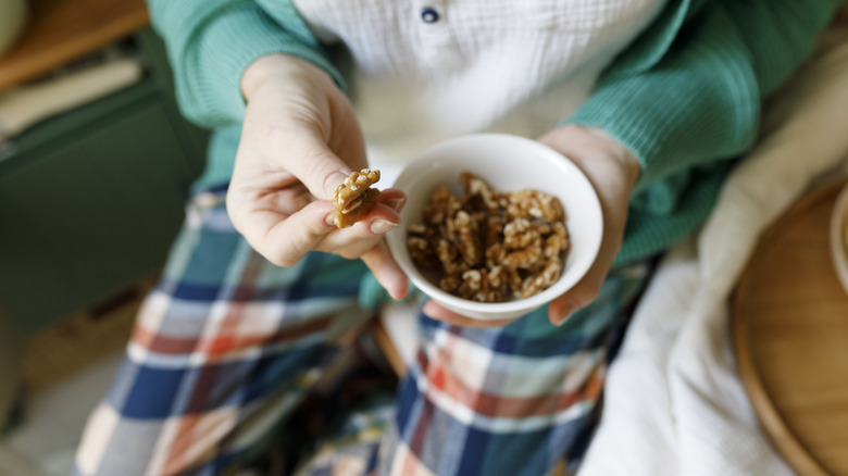 woman eating walnuts from bowl