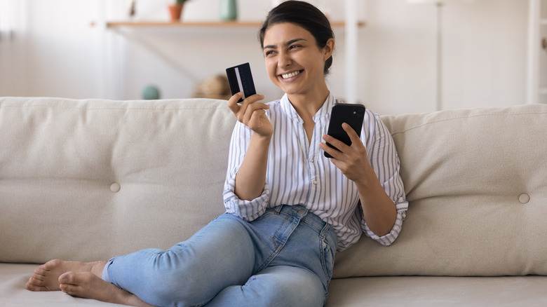 Woman delightedly sitting on her couch buying groceries