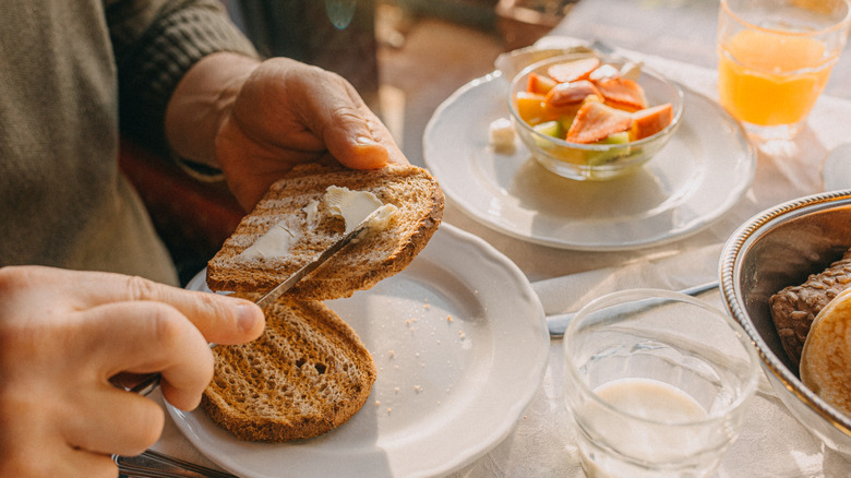 person spreading butter on toast