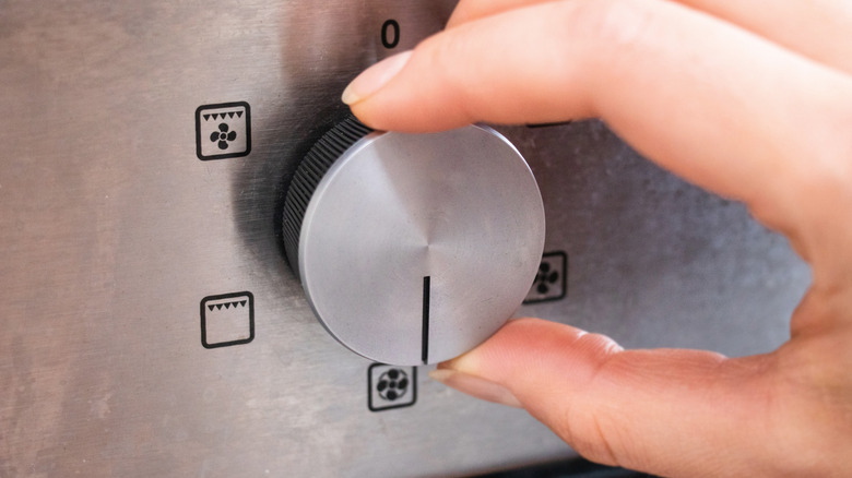 Hand turning dial on oven