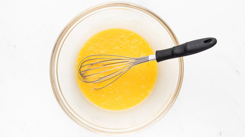 Whisking melted butter and eggs in glass bowl