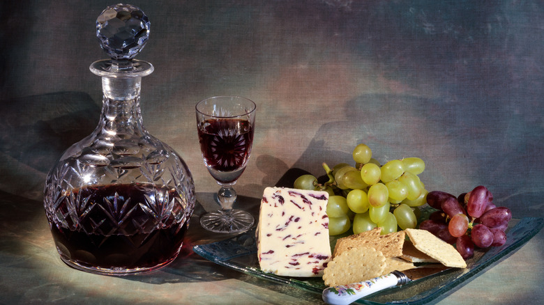 container of port wine with plate of cheese and grapes