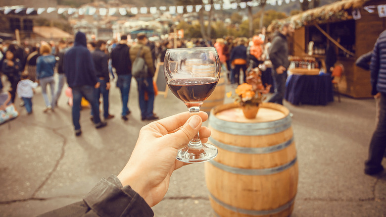 person holding up wine glass at outdoor festival