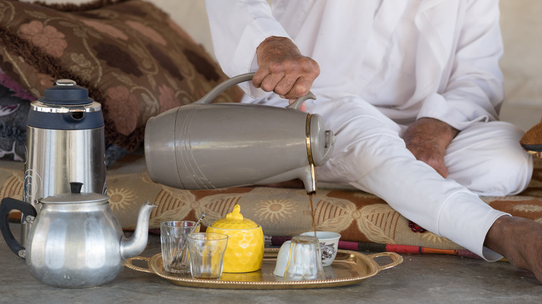 person pouring coffee onto overturned glass